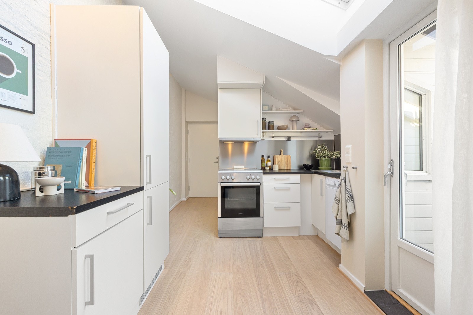 HTH-Kjøkkeninnredning fra 2012 med slette og hvite fronter og 28mm tykk og mørklaminert benkeplate av spon med nedfelt vaskekum i børstet stål og ettgreps blandebatteri i rustfritt stål. Galleribilde