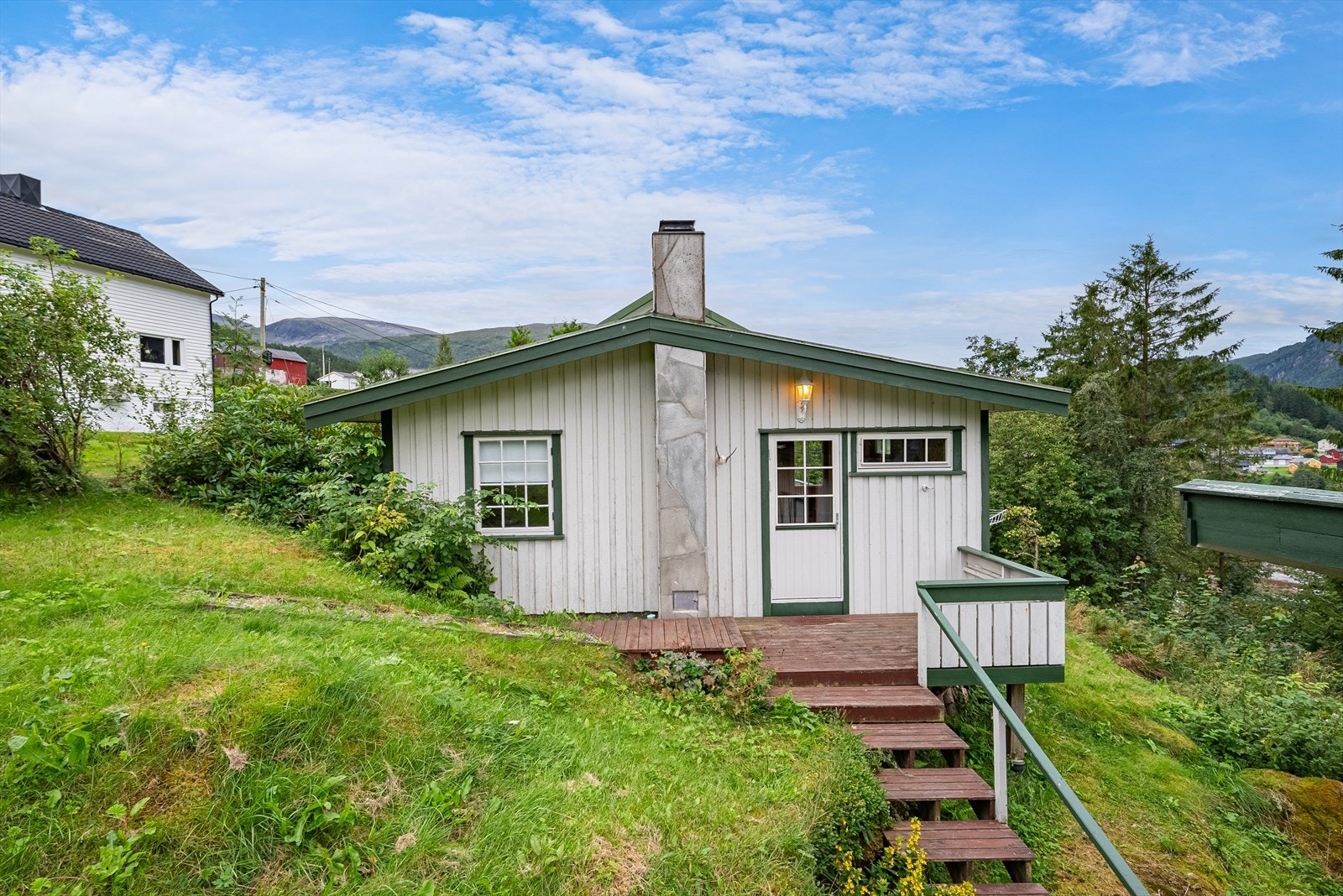 Fra stua i 1.etasje er det dør ut til verandaen hvor det er trapp videre ned til uthus og anneks. Galleribilde