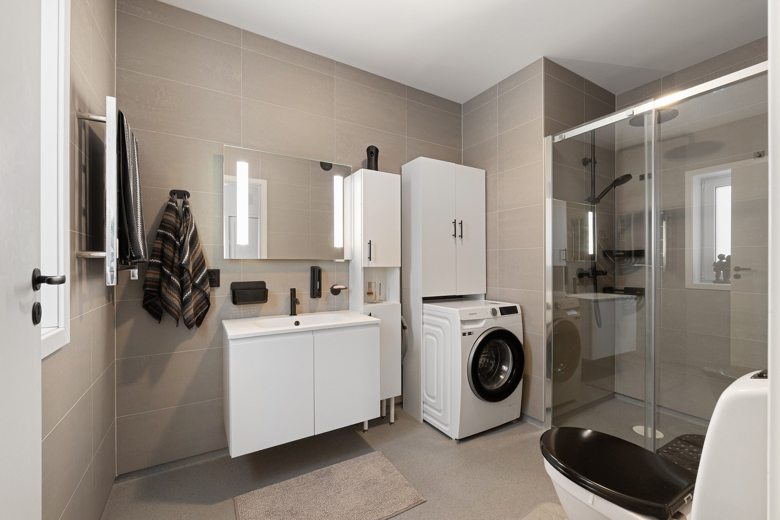 Med over 6 kvm. er badet større enn hva som vanligvis inngår i tilsvarende leiligheter. Den romslige dusjnisjen skjermes av skyvedør i glass. Galleribilde