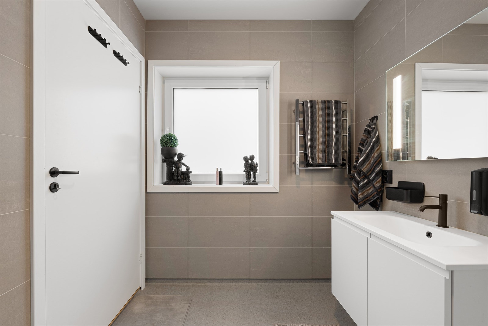 Badets gulv er utført med vinylbelegg, veggene med fliser. I gulvet er det elektrisk varme. Galleribilde