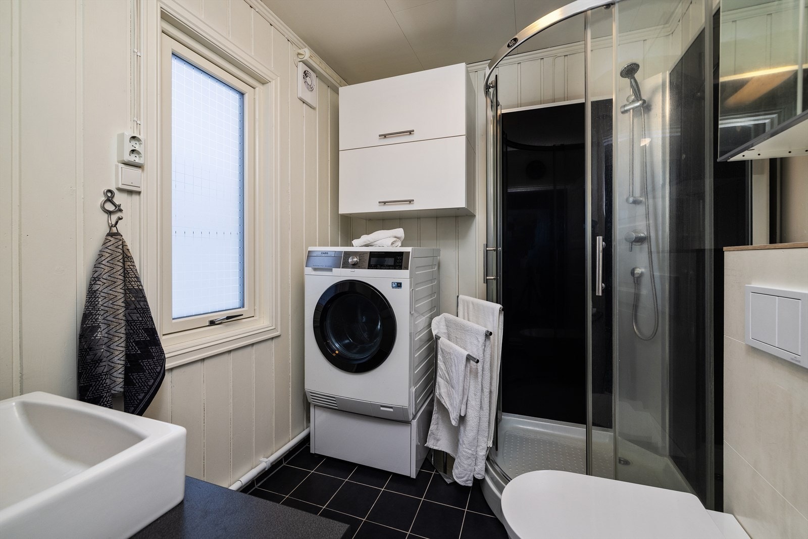 Rommet er utstyrt med dusjkabinett, vegghengt toalett og opplegg for vaskemaskin. Galleribilde