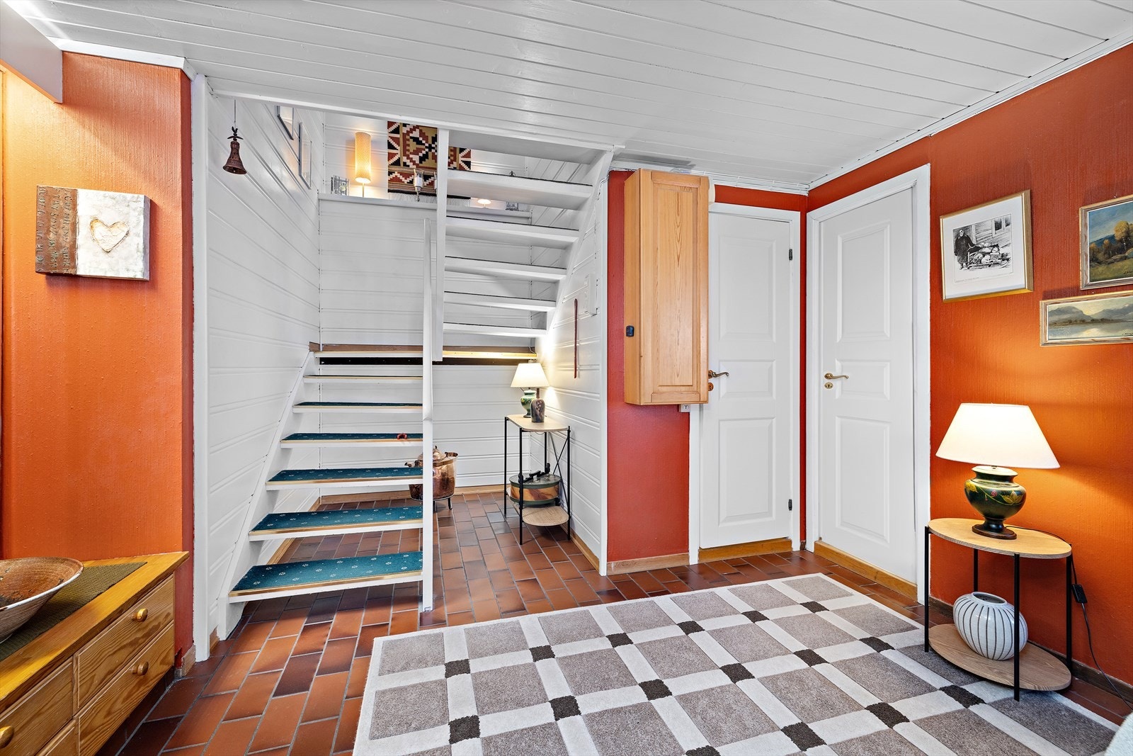 Den malte tretrappen med teppe på trinnene leder opp til boligens hovedetasje. Galleribilde