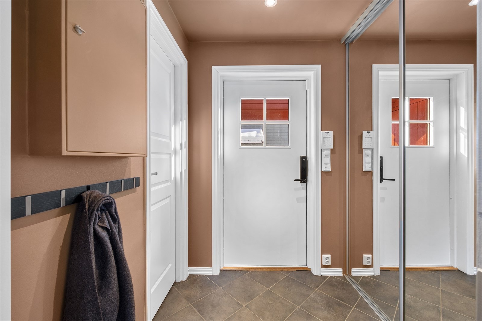 Innbyende entré med fliser på gulv med elektriske varmekabler. Inngangsdøren har Yale dørlås. Galleribilde