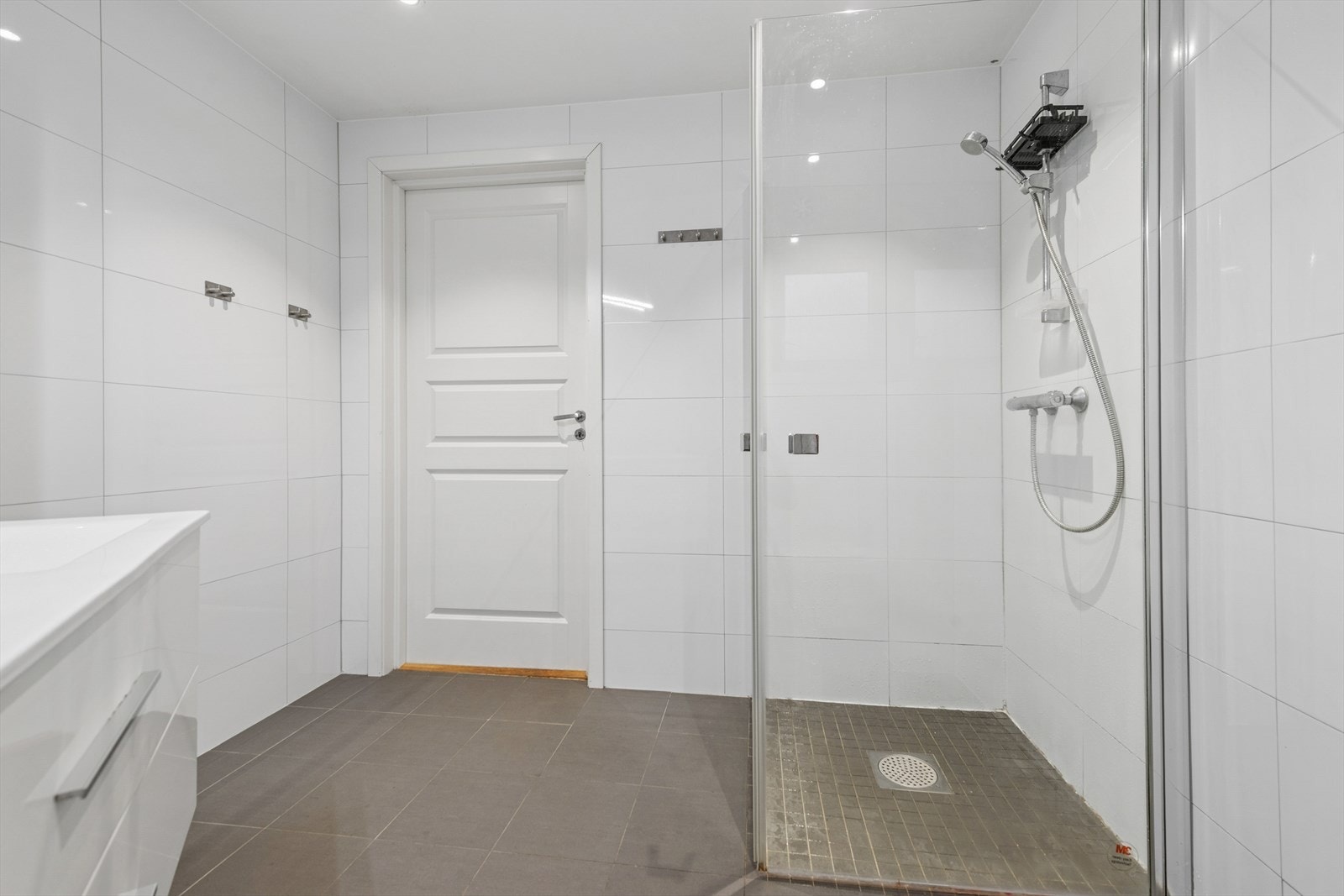 Rommet er innredet med dobbel servant, veggmontert toalett og dusjvegger. Gulvvarme gir behagelig komfort. Galleribilde