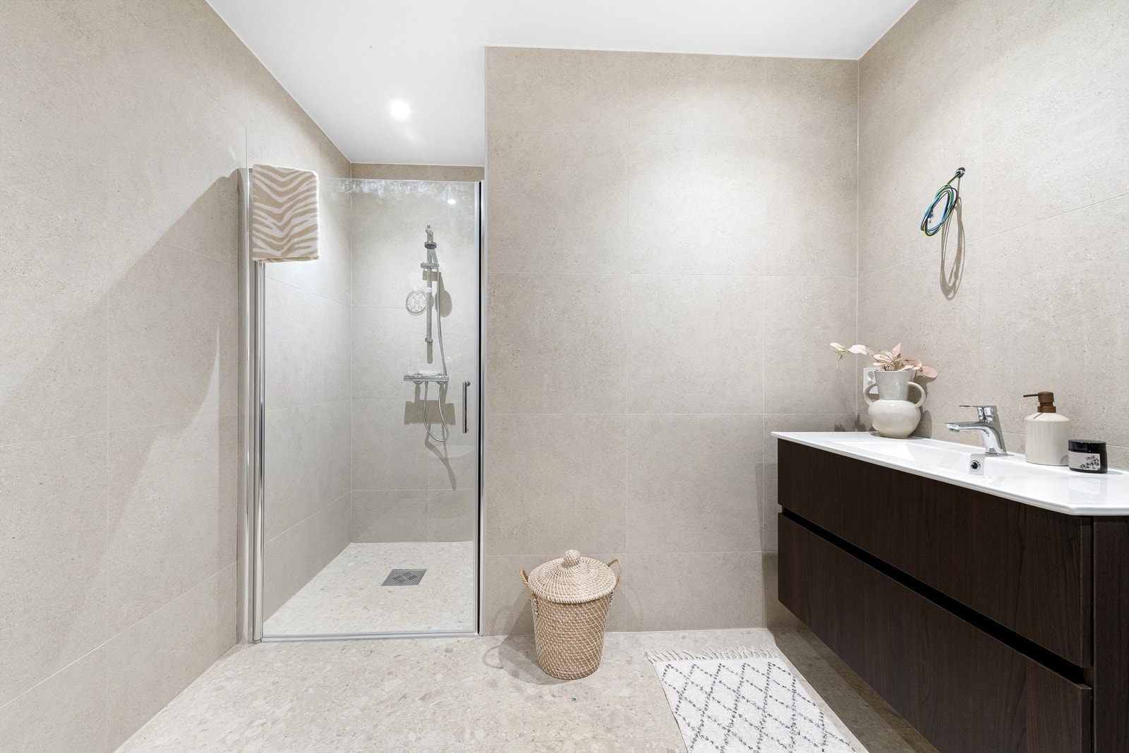 Delikat og romslig bad med moderne flisvalg, dusjsone og varmekabler i gulv. Galleribilde