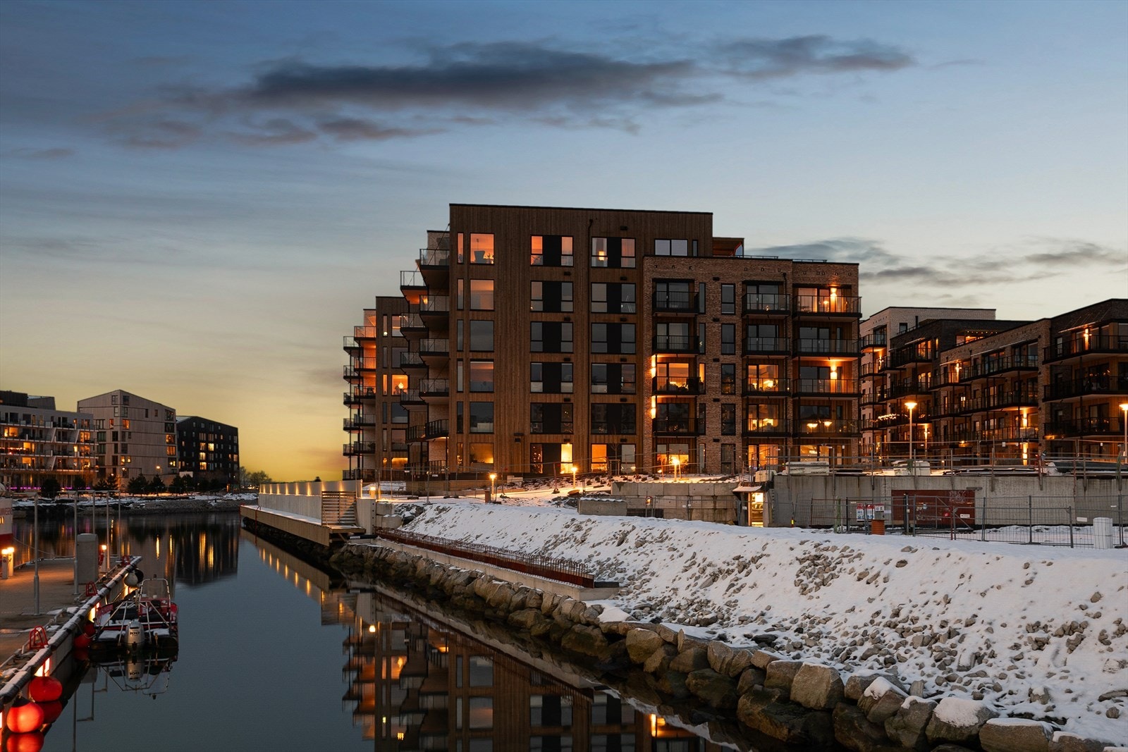 Eiendommen ligger vakkert til ved vannkanten, hvor kveldshimmelen og den rolige havnen danner en stemningsfull ramme rundt bebyggelsen. Galleribilde