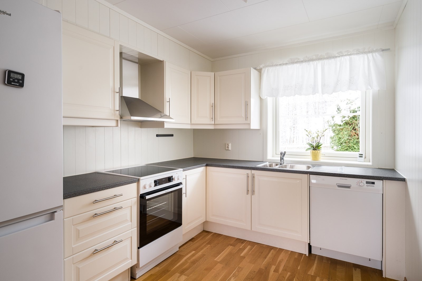 Innredningen har lyse, profilerte fronter og koksgrå laminatbenkeplate med nedfelt kum i stål. Galleribilde