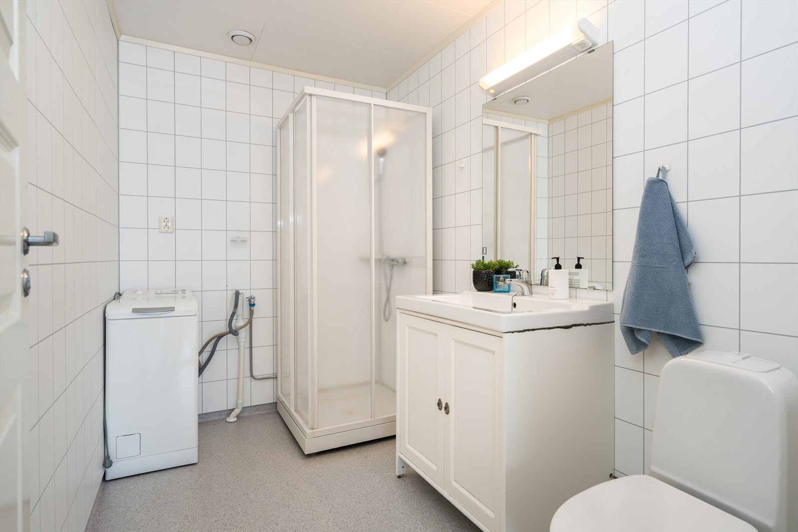 Baderomsinnredningen har hvite, profilerte fronter og består av en heldekkende servant på en skapseksjon og et stort speil med belysning. Galleribilde