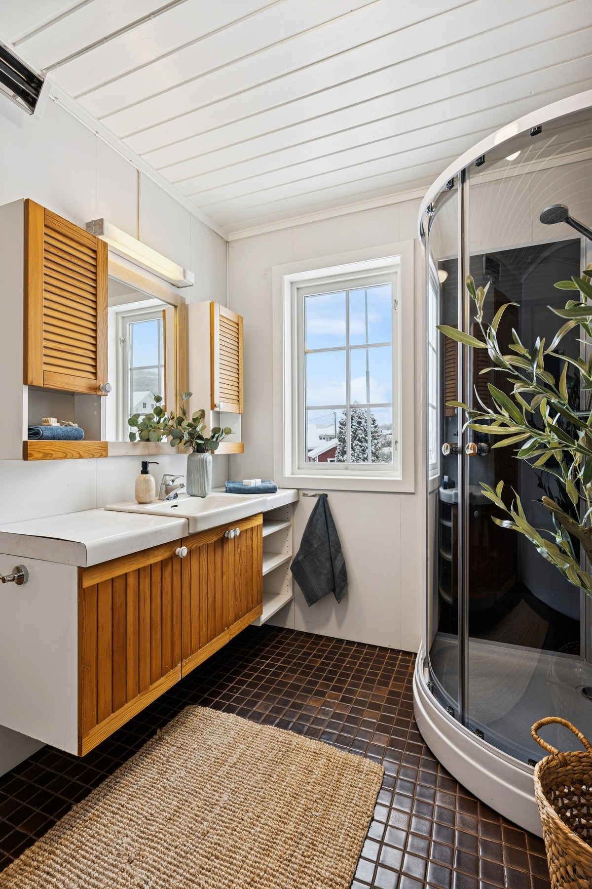 Bad med flislagt gulv, dusjkabinett, servantinnredning og toalett. Galleribilde