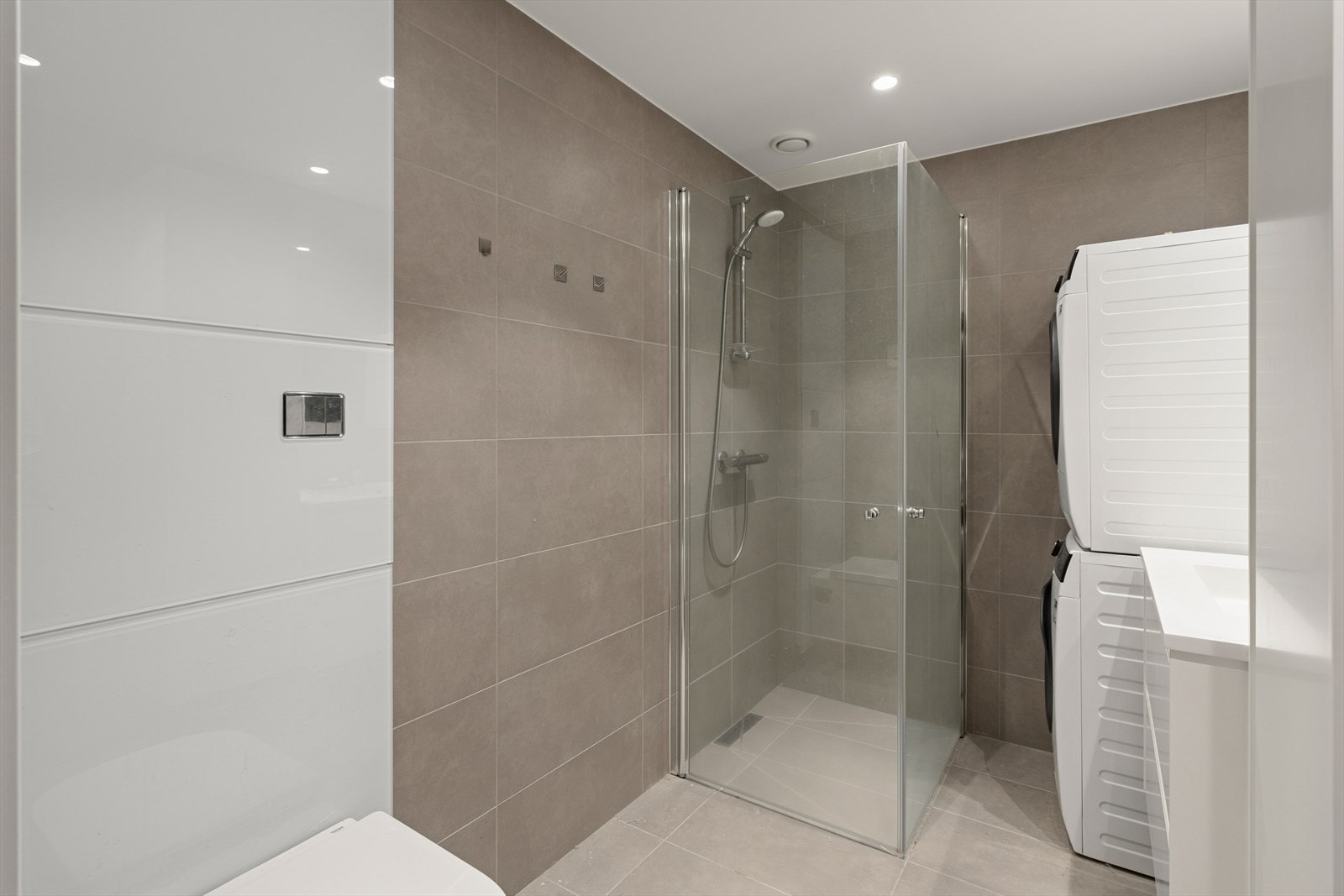 Flislagt baderom med opplegg for vaskemaskin og innfellbare dusjvegger. Galleribilde