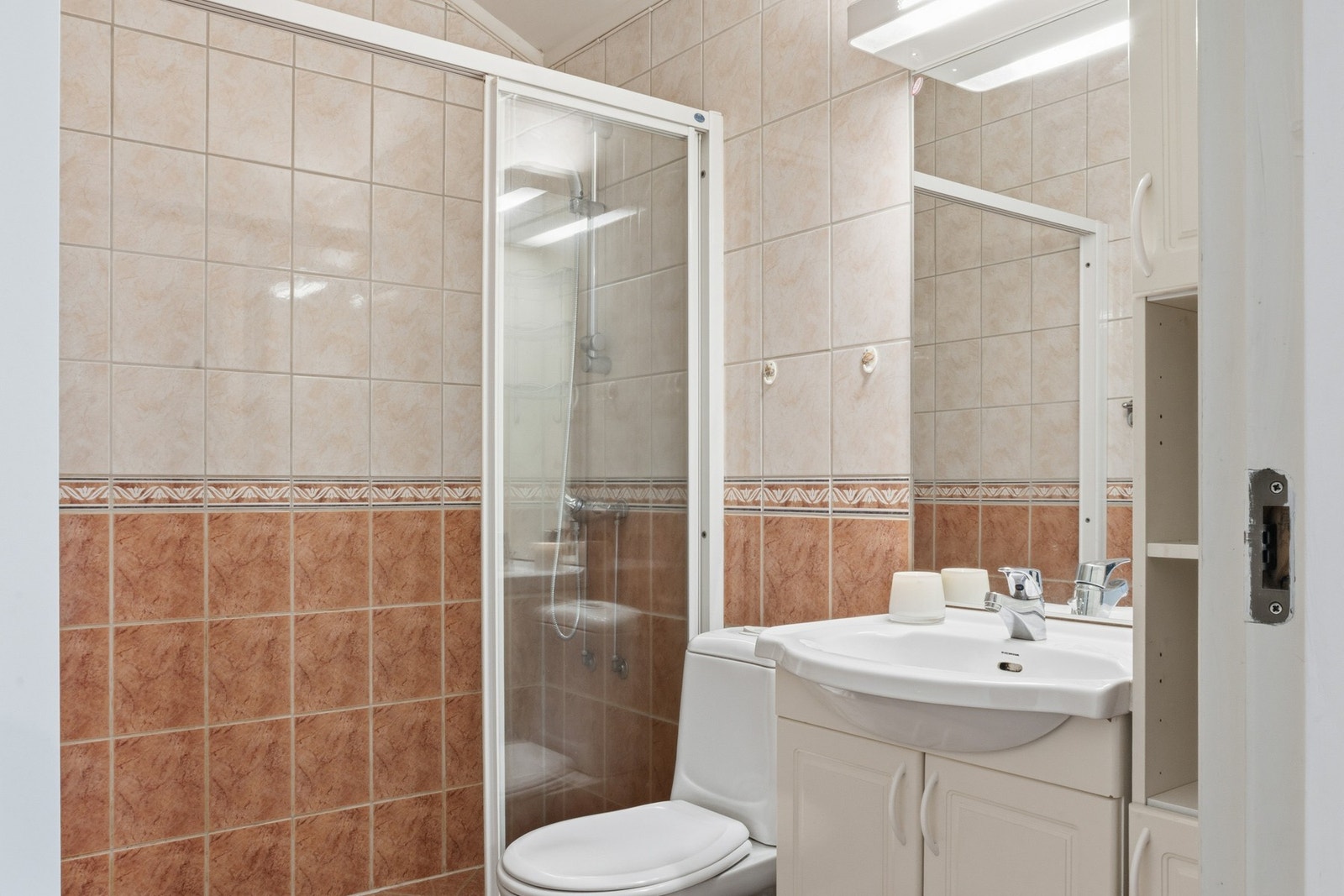 Badet er innredet med dusj, toalett og servant med innredning. Galleribilde