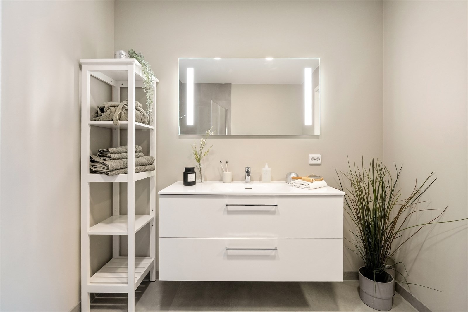 Moderne innredet med vegghengt toalett, dusjhjørne med foldbare dører, speil med belysning og hel servant med god oppbevaringsplass i baderomsmøbel. Galleribilde