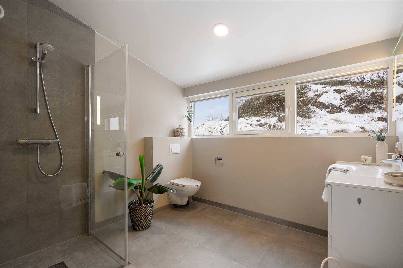 Hovedsoverommets bad er moderne innredet med vegghengt toalett, dusjhjørne med foldbare dører, speil med belysning og hel servant med god oppbevaringsplass i baderomsmøbel. Galleribilde