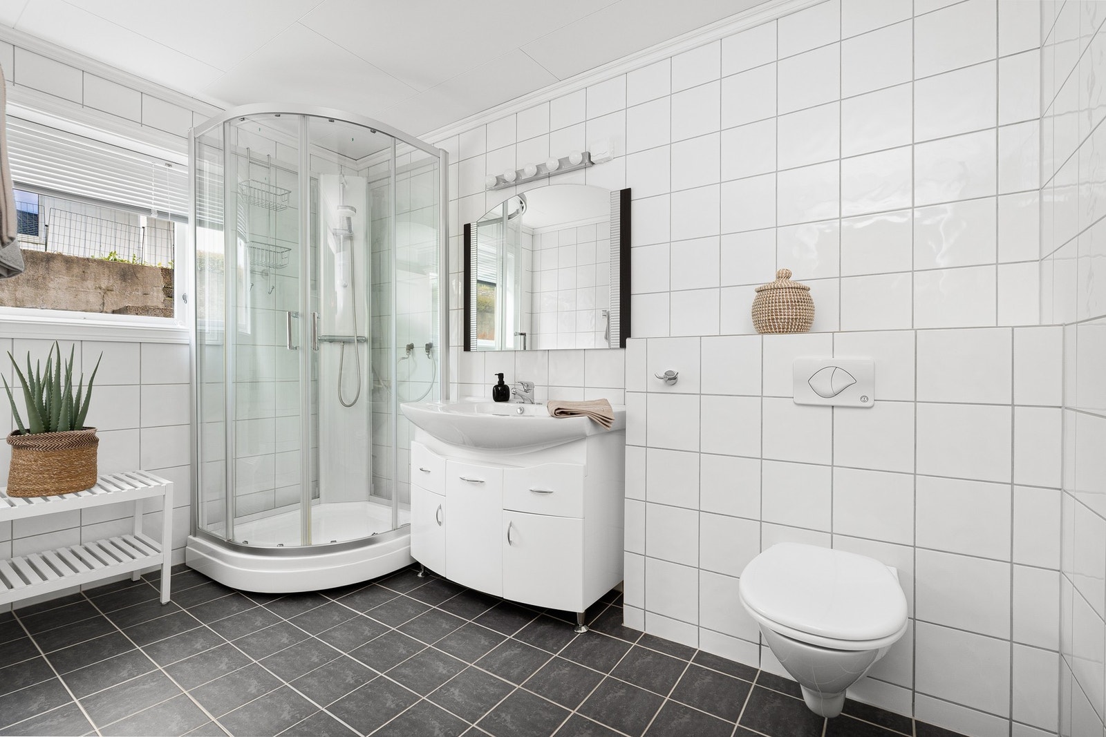 Lyst og lekkert fliselagt baderom renovert ca 2005. Badet inneholder vegghengt toalett, innredning med vask og dusjkabinett. Galleribilde