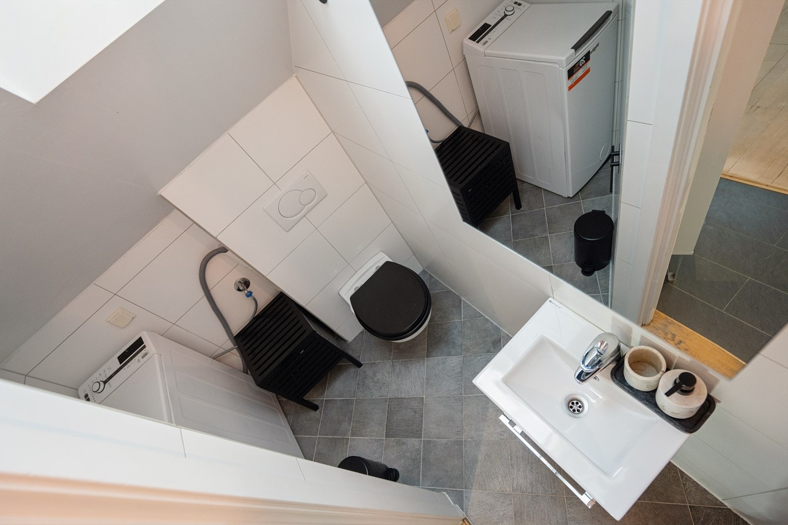 Flislagt baderom med dusj, vegghengt toalett og vaskemaskin blant annet Galleribilde