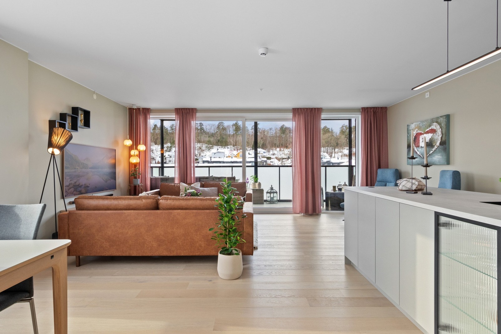 Stue og kjøkken danner et åpent, sosialt og innbydende allrom, hvor store vindusflater i to retninger gir rikelig med naturlig lys og fine utsiktsforhold. Galleribilde