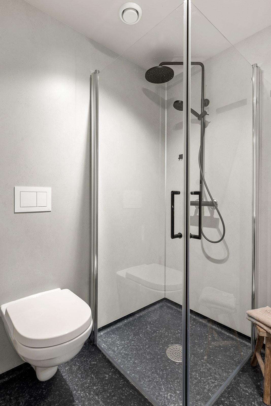 Badet har veggmontert toalett, dusjhjørne med innfellbare glassdører og opplegg for vaskemaskin. Galleribilde