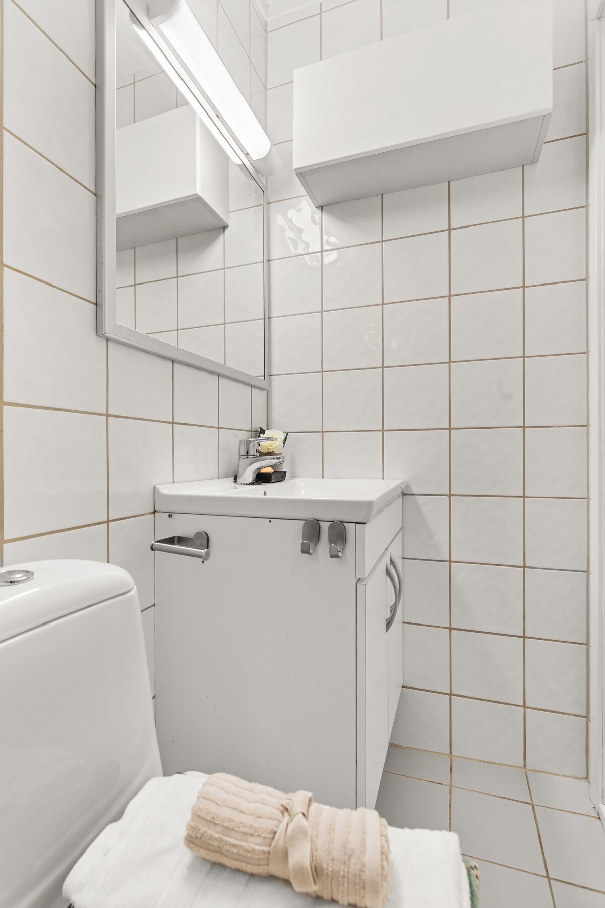 Badet er utstyrt med dusjnisje med skyvedør, servant med skap, speil med lys, veggskap, gulvmontert wc Galleribilde