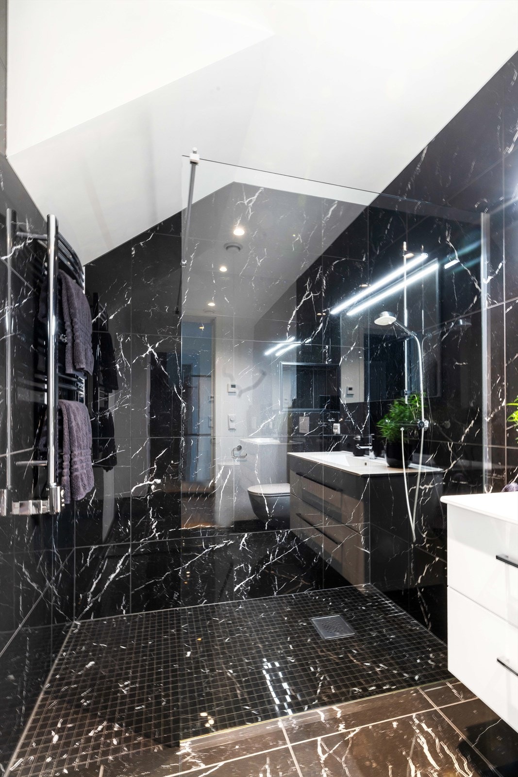 Baderommet inneholder vegghengt toalett, romslig dusjnise og servant med oppbevaring. Galleribilde