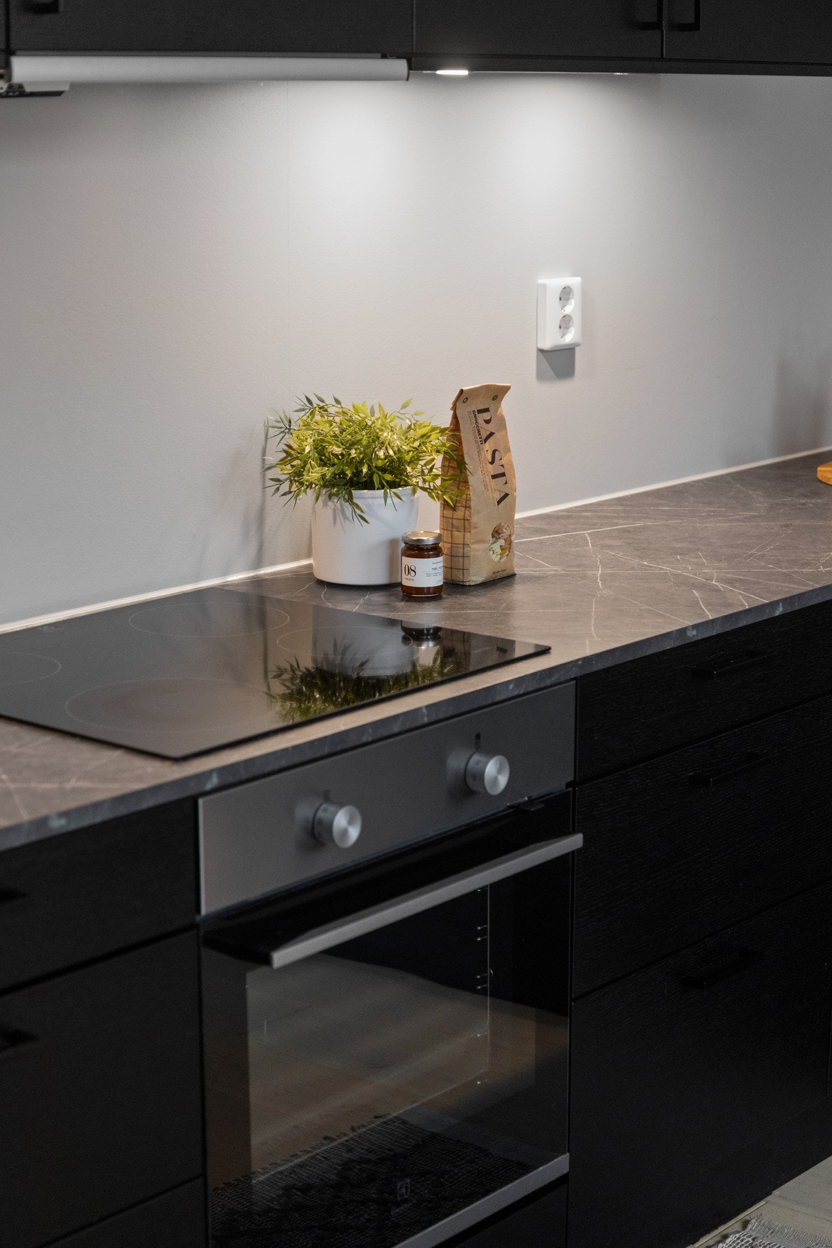 Innredningen har sorte, glatte fronter og grå laminatbenkeplate med underlimt kum i stål. Galleribilde