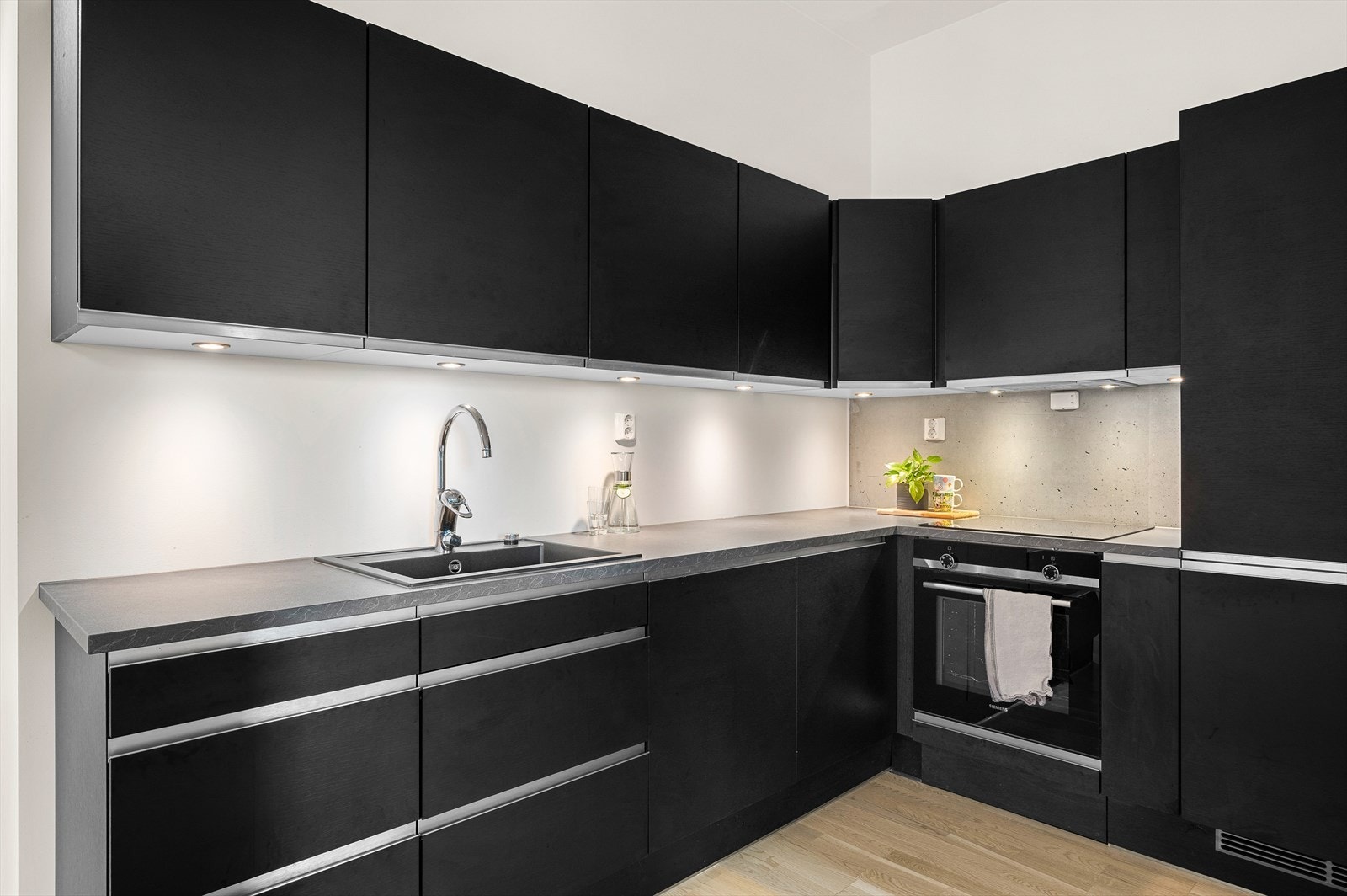 Den mørke kjøkkeninnredningen fra JKE består av mekanisk avtrekksvifte over stekesone. Galleribilde