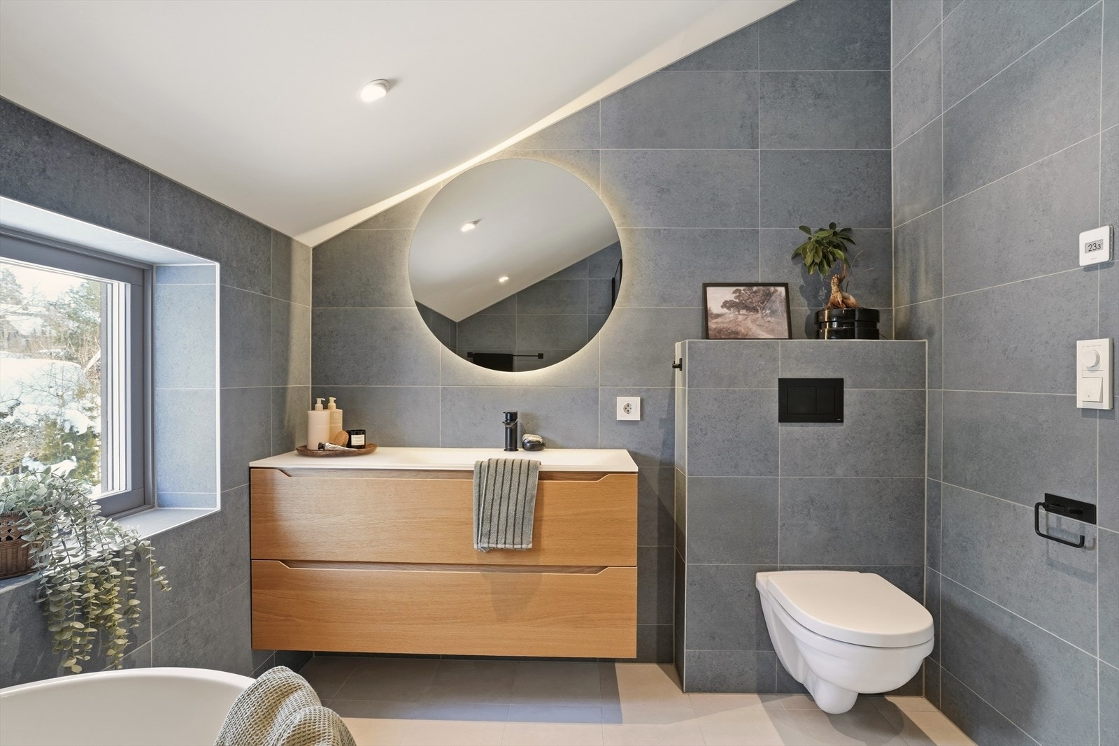 Badet i 2.etasje har nedfelt servant med skuffer under, speil med lys rundt og veggmontert toalett. Galleribilde