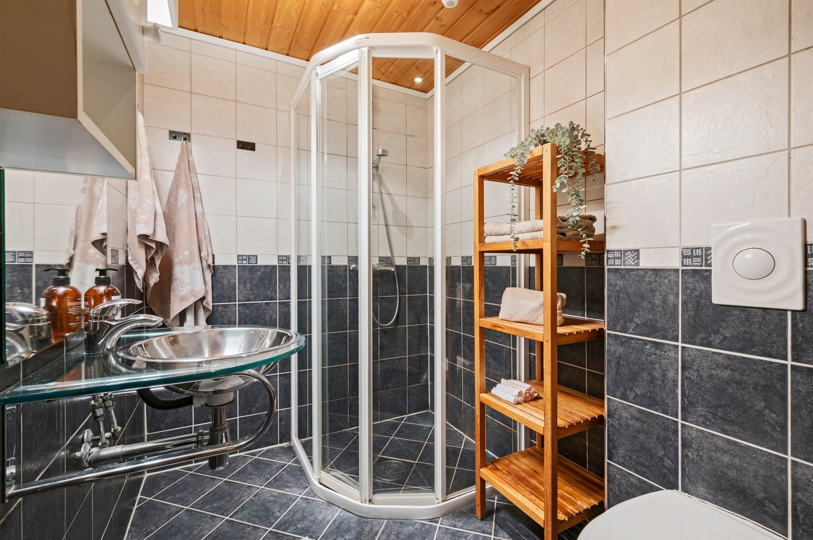 Pent flislagt bad med servant med overskap og speil med lys, dusjhjørne og toalett. Rommet er ikke godkjent for varig opphold. Galleribilde