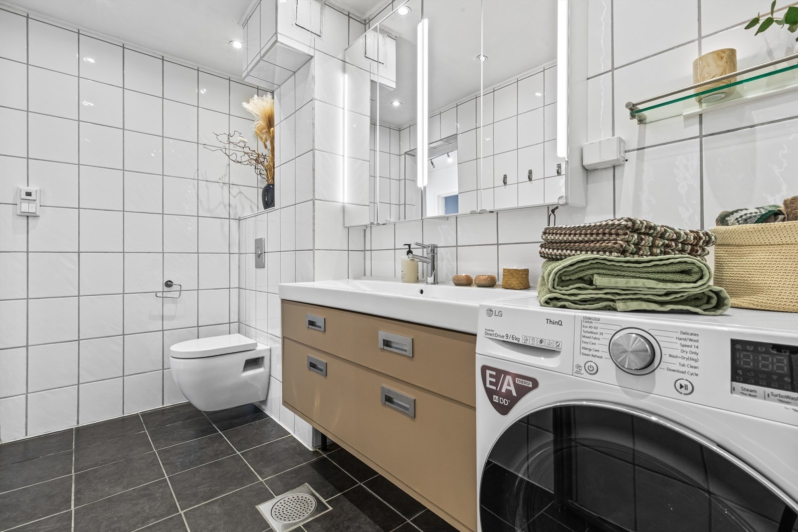 Innredningen består av heldekkende servant med underskap, speilskap, veggmontert WC og dusjsone med to svingbare glassvegger. Det er opplegg for vaskemaskin. Deler av baderomsinnredningen var ny i 2019. Galleribilde