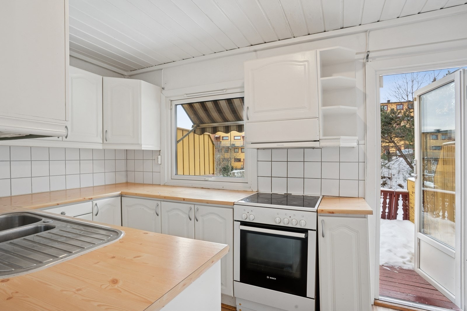 Kjøkken med profilerte fronter og direkte utgang til en stor terrasse. Galleribilde