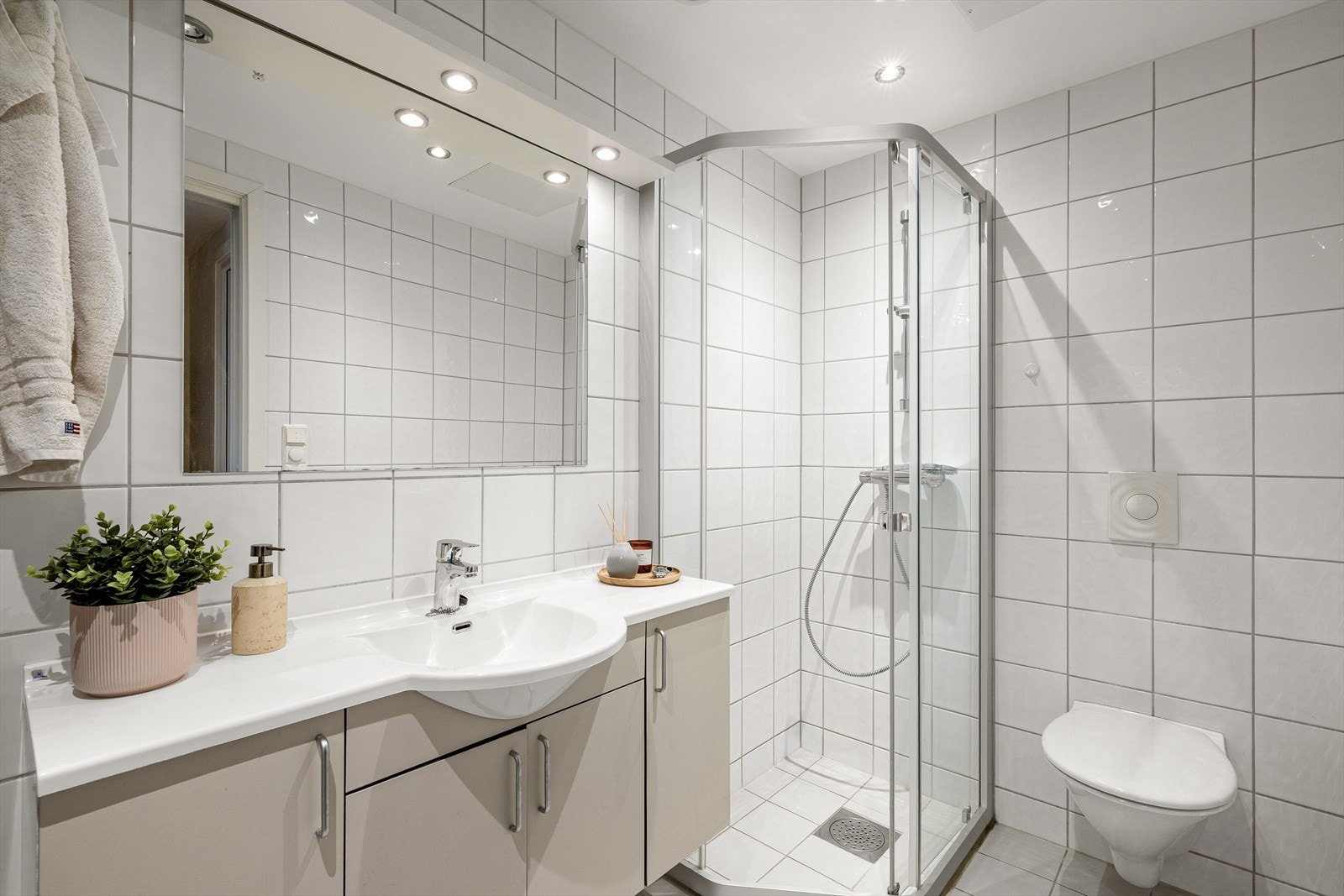 Badet er helfliset og har elektriske varmekabler i gulvet. Rommet er utstyrt med vegghengt toalett og dusjhjørne. Galleribilde