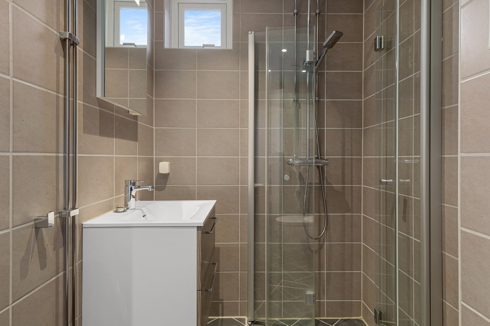 Badet er utstyrt med toalett, dusjhjørne og servant med innredning. Galleribilde