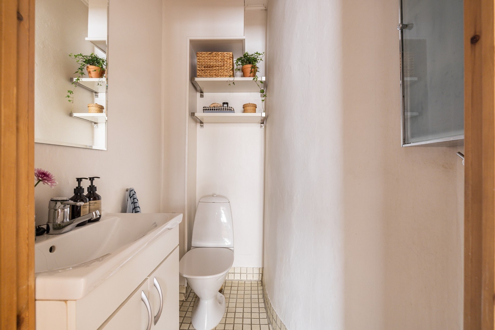 Rommet er utstyrt med vegghengt servantskap med speil over og gulvstående toalett. Praktiske vegghyller for lagring. Galleribilde