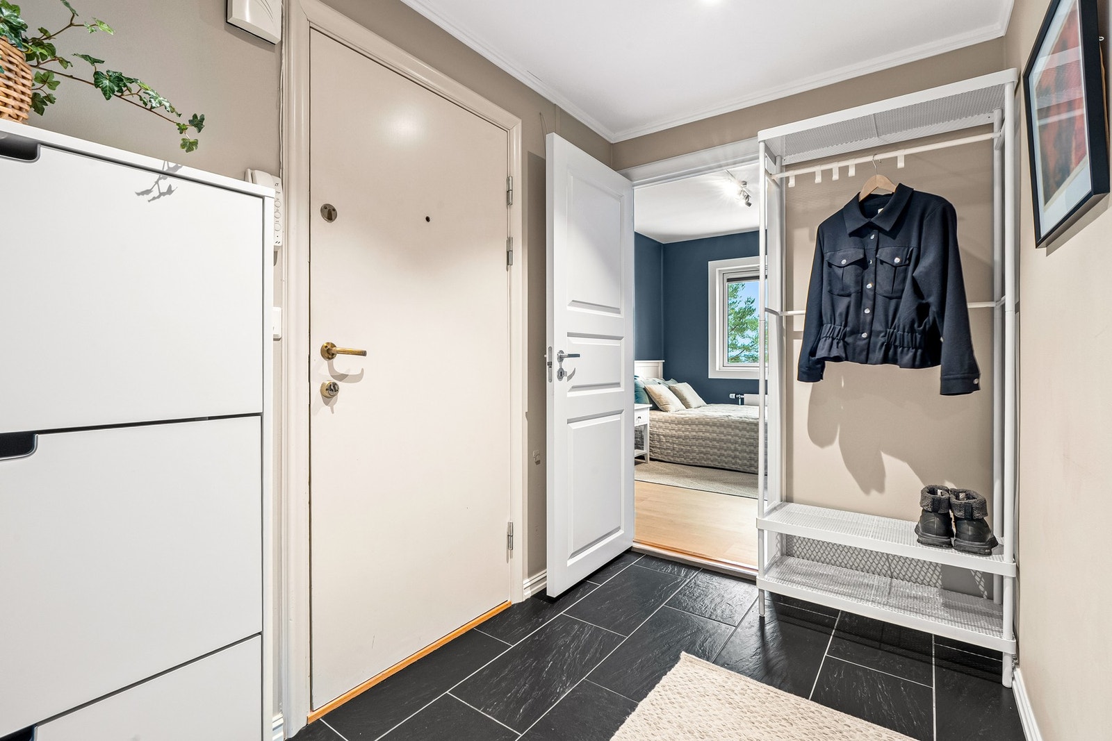 Pen entré med lysmalte vegger, downlights i himlingen og mørke fliser på gulvet. Galleribilde