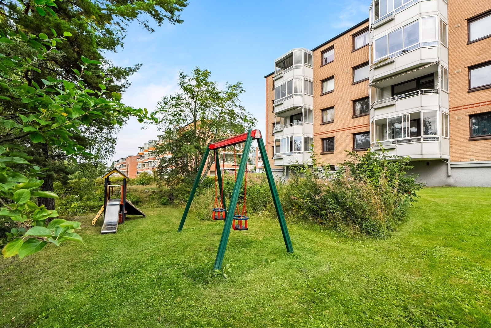 Rundt og mellom bebyggelsen er det et sosialt fellesområde med plen, sittegrupper, grillplass og flere lekeapparater. Galleribilde