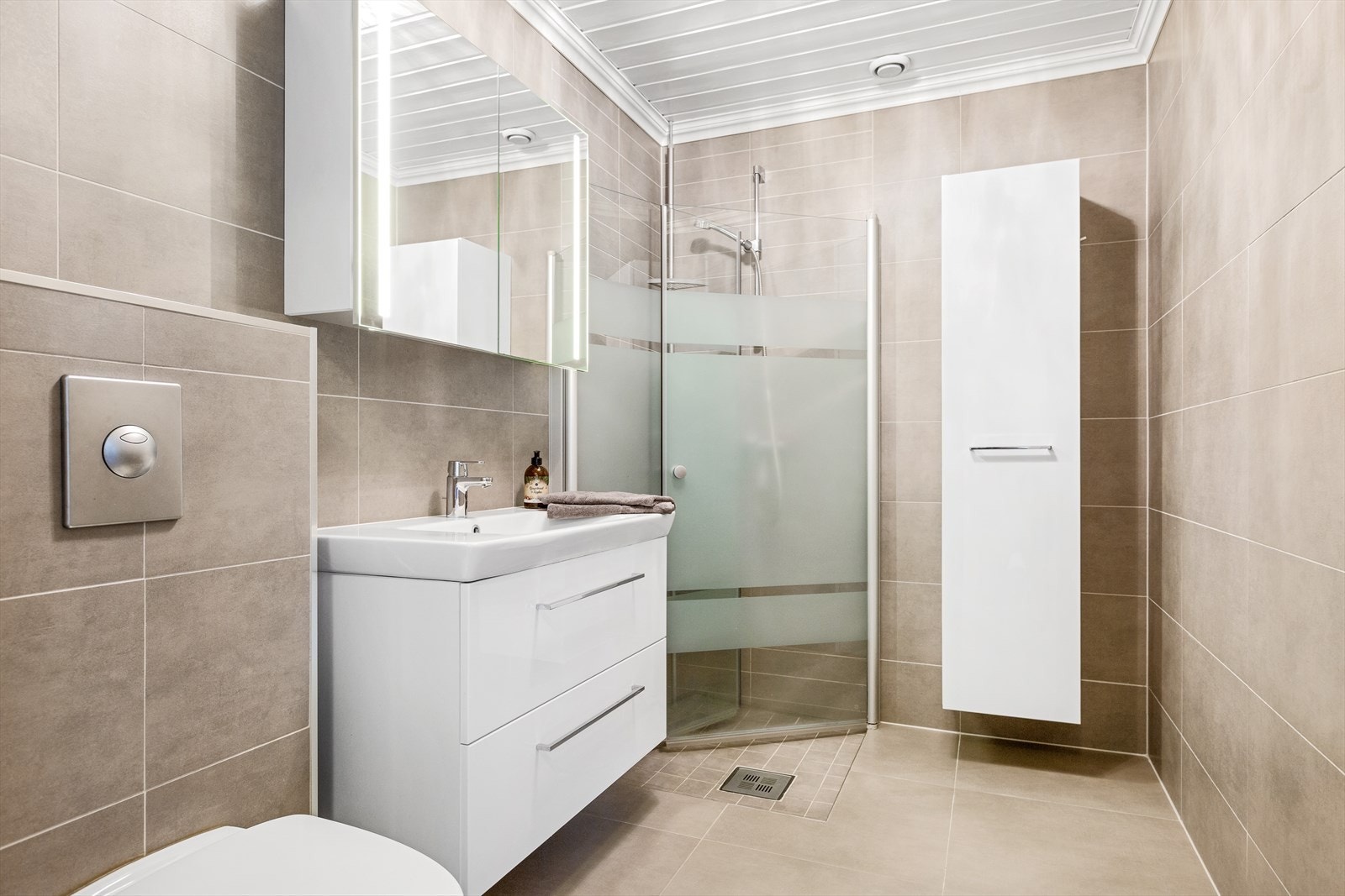 Badet i 1. etg med vegghengt toalett, dusjhjørne med innfellbare glassdører, samt servant med underskap og et vegghengt høyskap Galleribilde