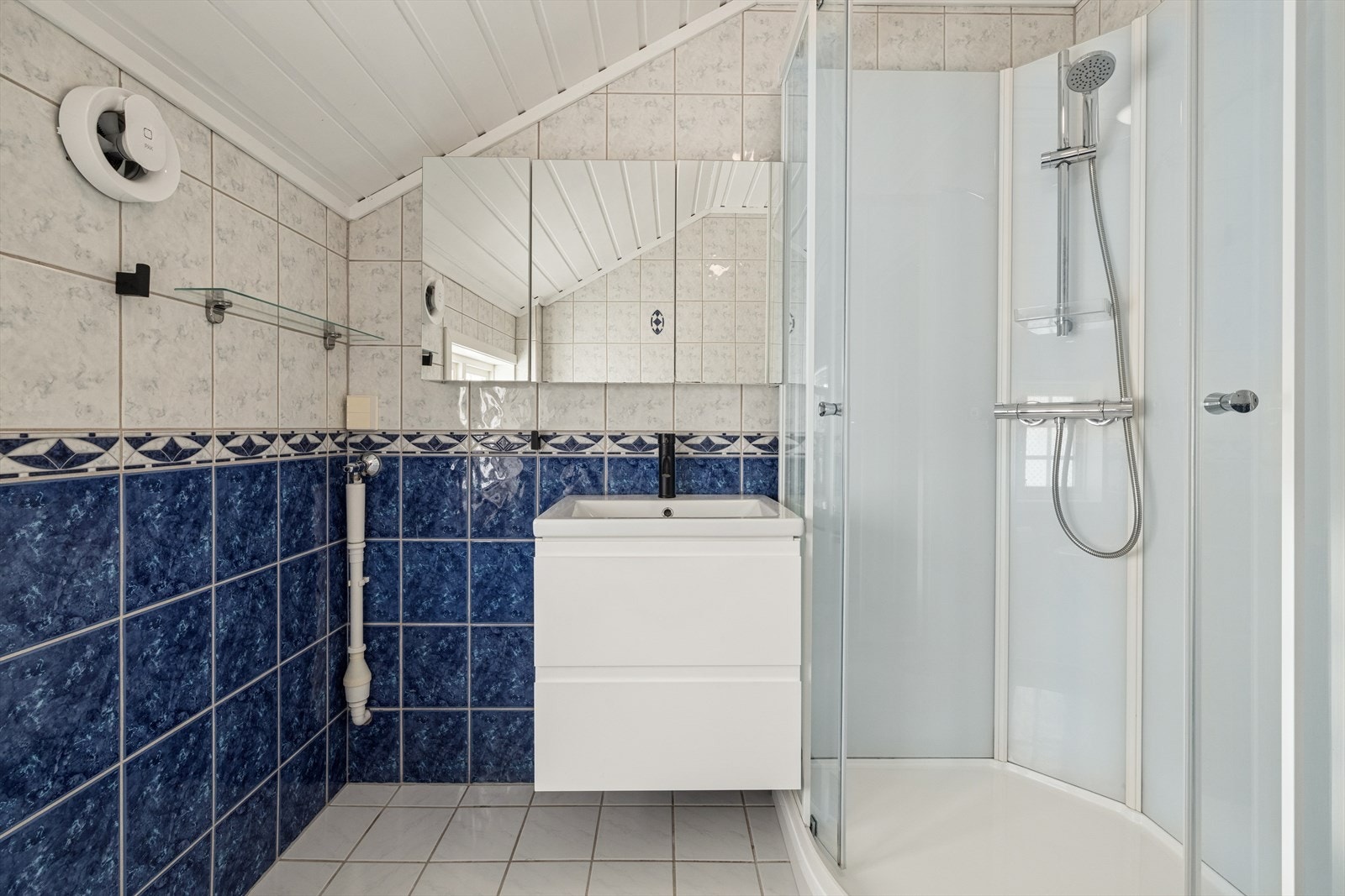 Badet (fra byggeår) er flislagt på gulv og vegger, med malt panel i himling og elektriske varmekabler i gulvet. Rommet er utstyrt med WC, servant og dusjkabinett, og har elektrisk styrt vifte for ventilasjon. Galleribilde