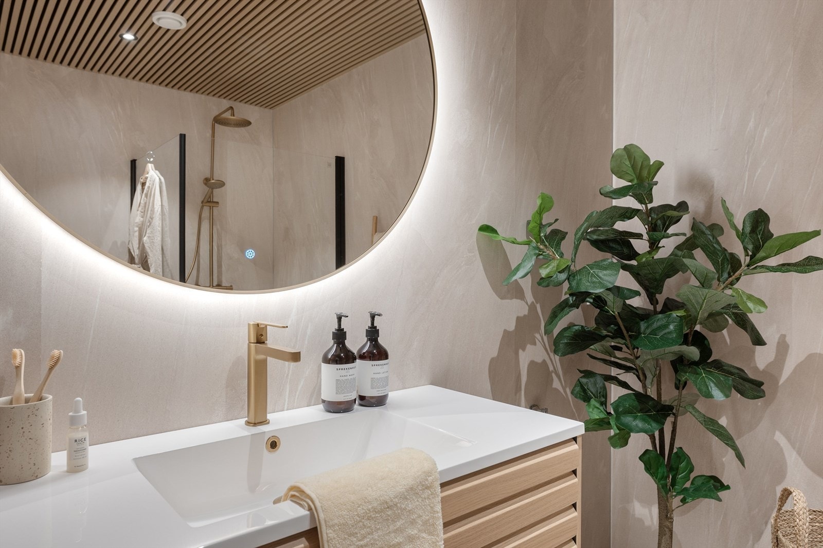 Rommet har innredning med servant, underskap i eik, speil med belysning, kran og dusj garnityr i børstet gull. Galleribilde