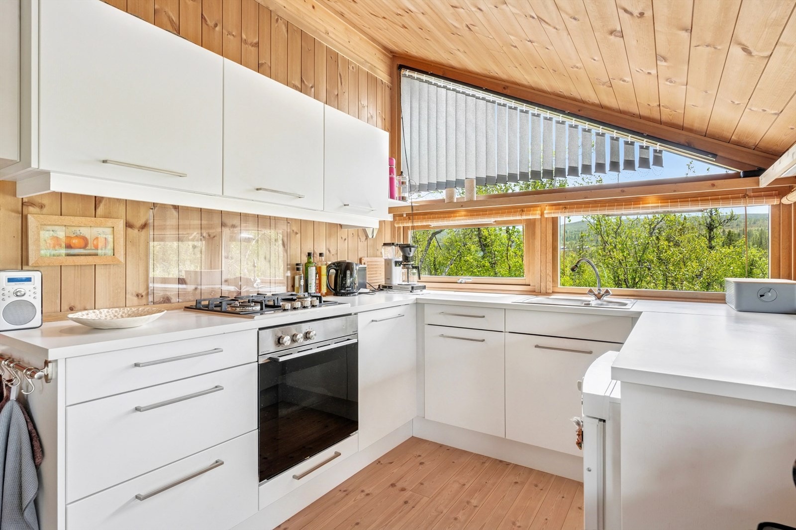 Kjøkkeninnredning med hvite fronter, laminat benkeplate og nedfelt utslagskum i rustfritt stål. Galleribilde