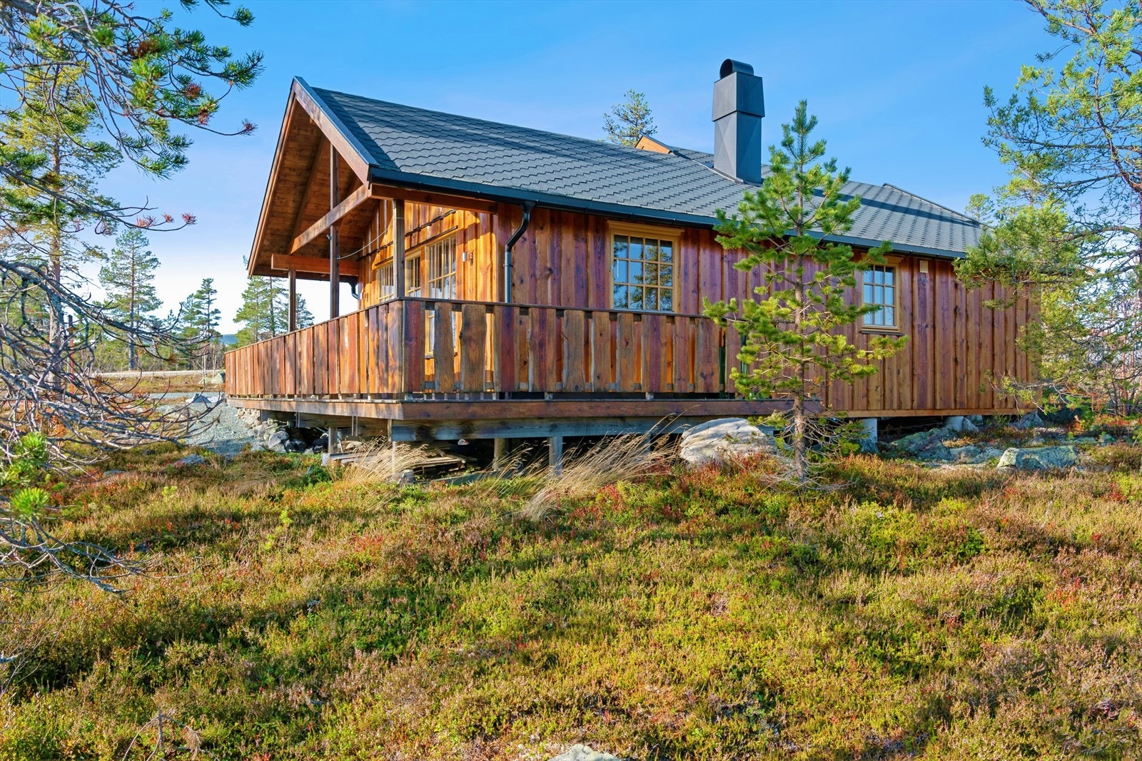 Hytta har en klassisk utforming med stående villmarksbordkledning og en romslig veranda. Galleribilde