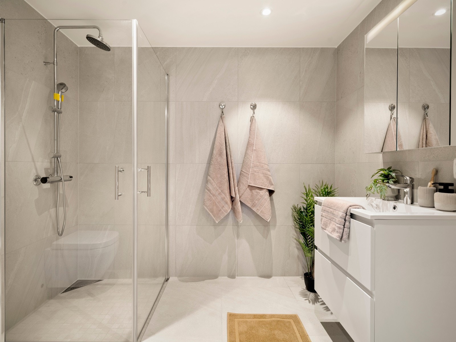 Lyst og oppgradert bad i tilknytning til hovedsoverommet, med regndusj i krom og fliser i Nordic Stone Islanda 60x60 på gulv og vegger, samt mindre mosaikkfliser på gulv i dusjsonen. Galleribilde