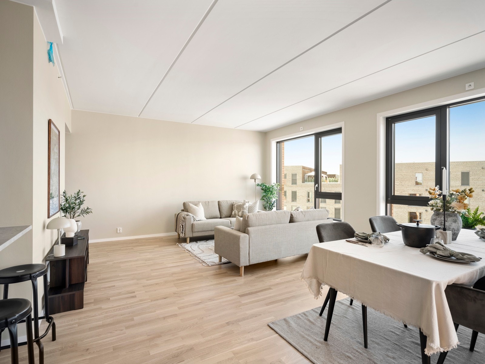 Romslig stue med god takhøyde og store gulv-til-tak-vindusflater i flere himmelretninger som slipper inn rikelig med naturlig lys. Enkelte av vinduene har påkostet utvendig solskjerming for økt komfort og fleksibel lysstyring. Galleribilde