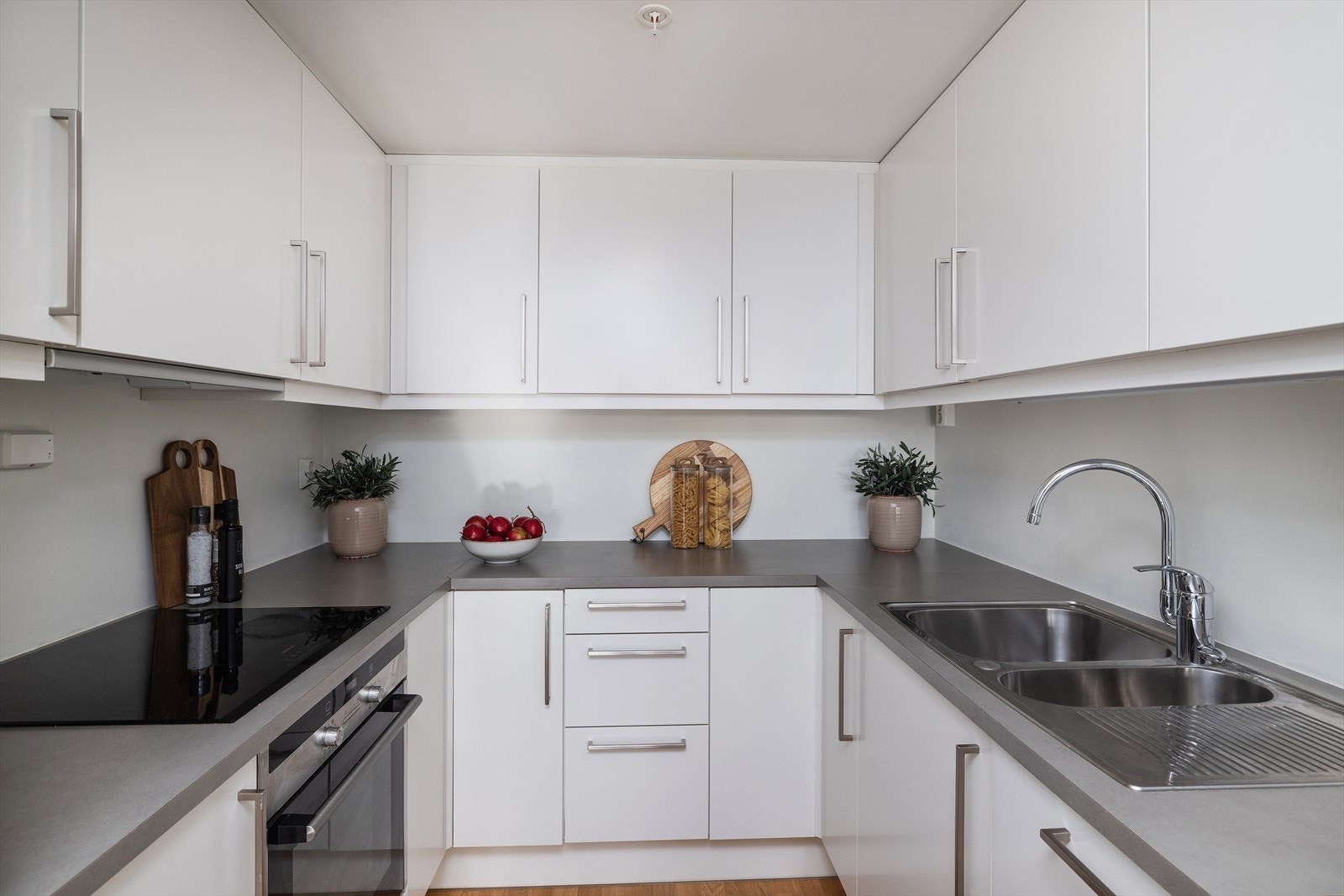 Praktisk U-formet kjøkkeninnredning fra 2014 med integrert stekeovn og induksjonstopp. Galleribilde