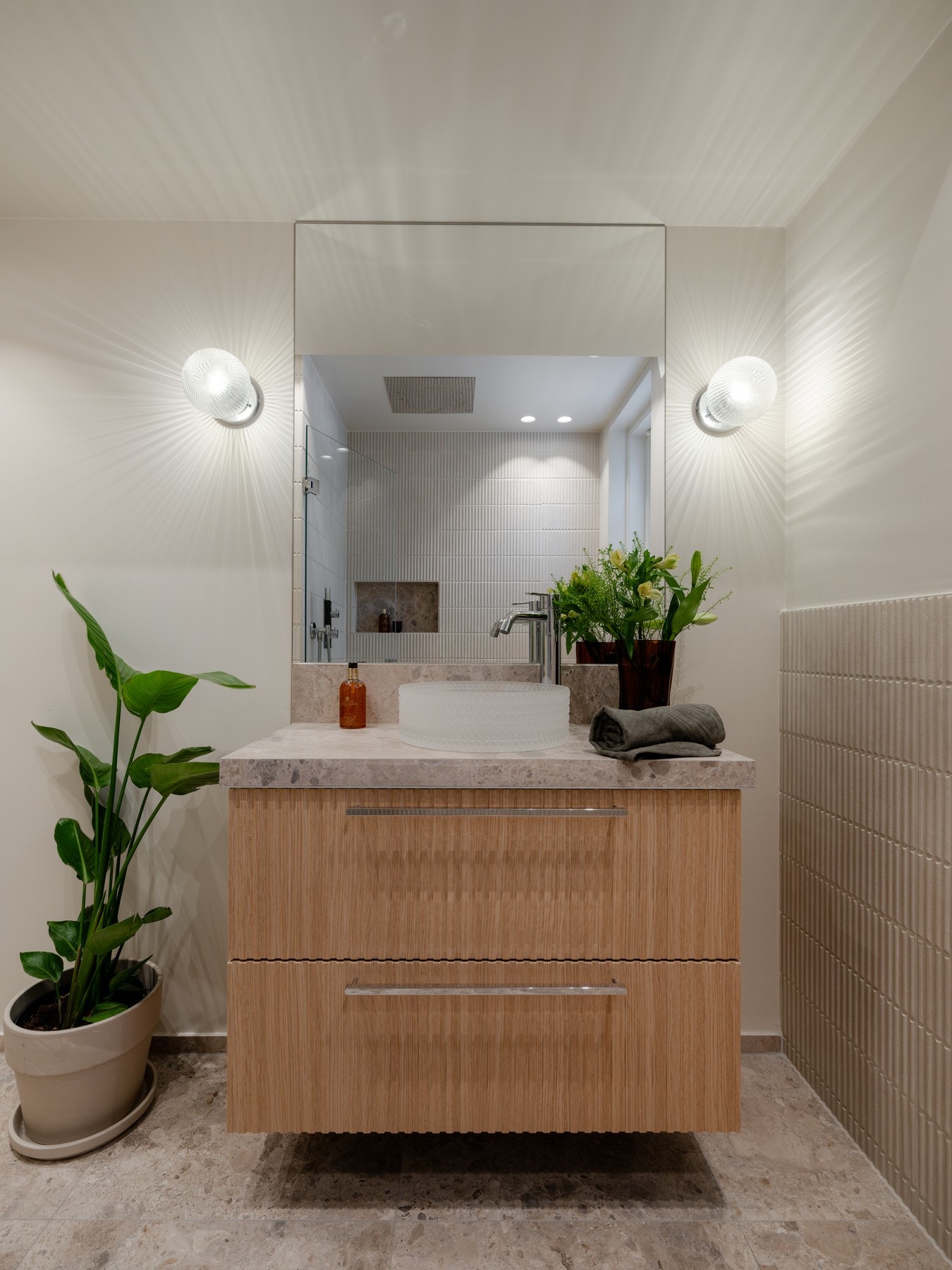 Innredningen består av ovenpåliggende servant på underskuffer, stort speil med belysning på sidene og vegghengt toalett. Galleribilde