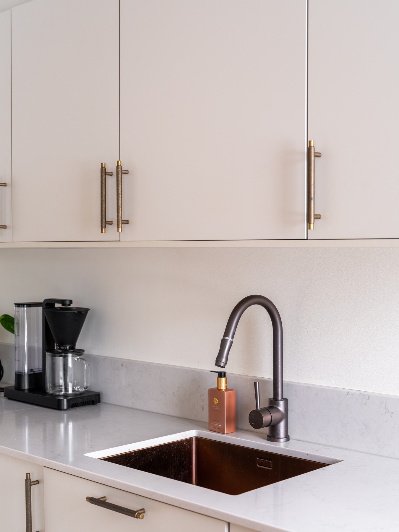 Grå, glatt innredning med benkeplate av stein og oppvaskkum med ett-greps armatur. Galleribilde