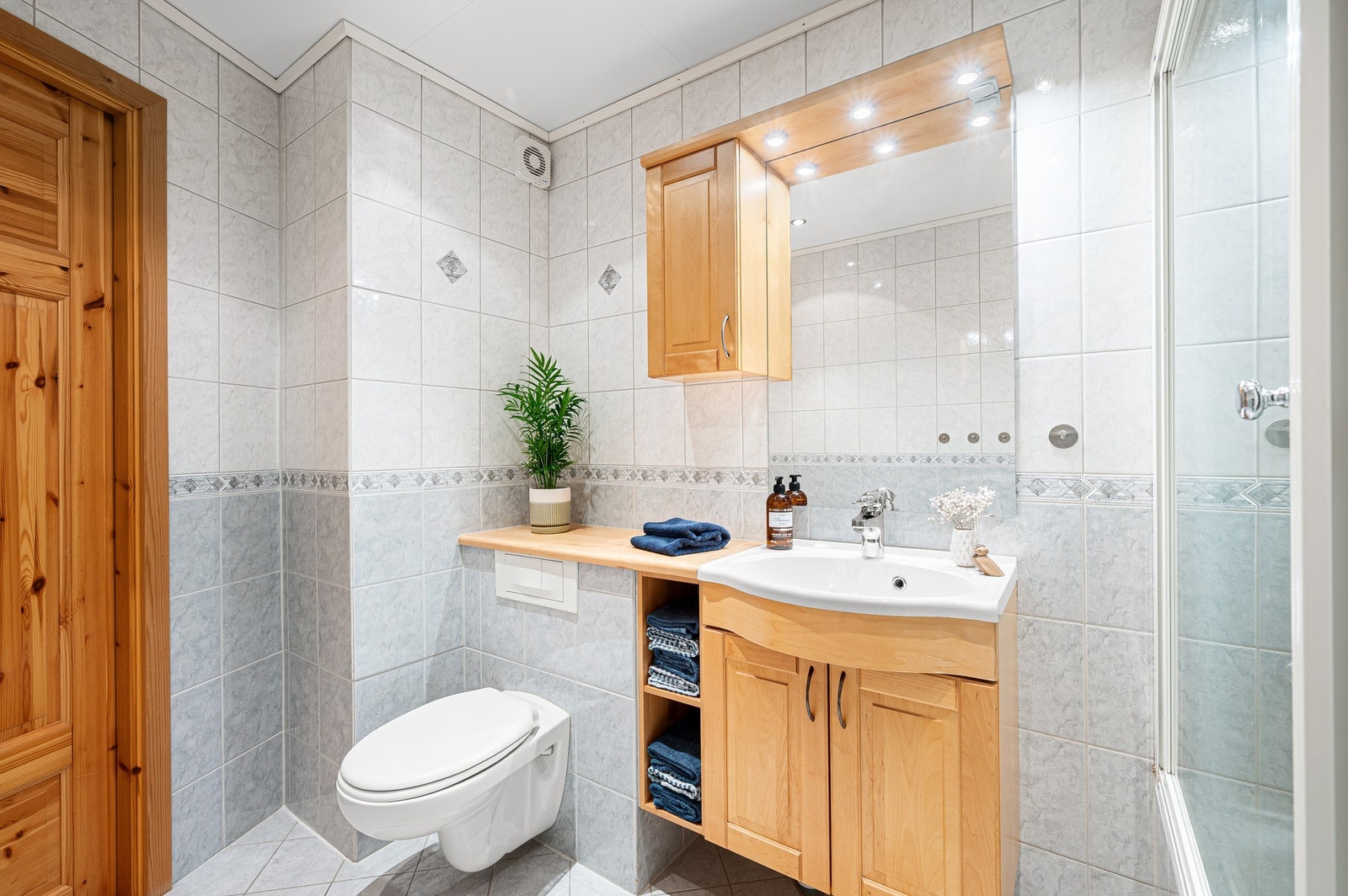 Badet er utstyrt med vegghengt servantskap og WC, og dusjgarnityr over innbygget badekar. Galleribilde