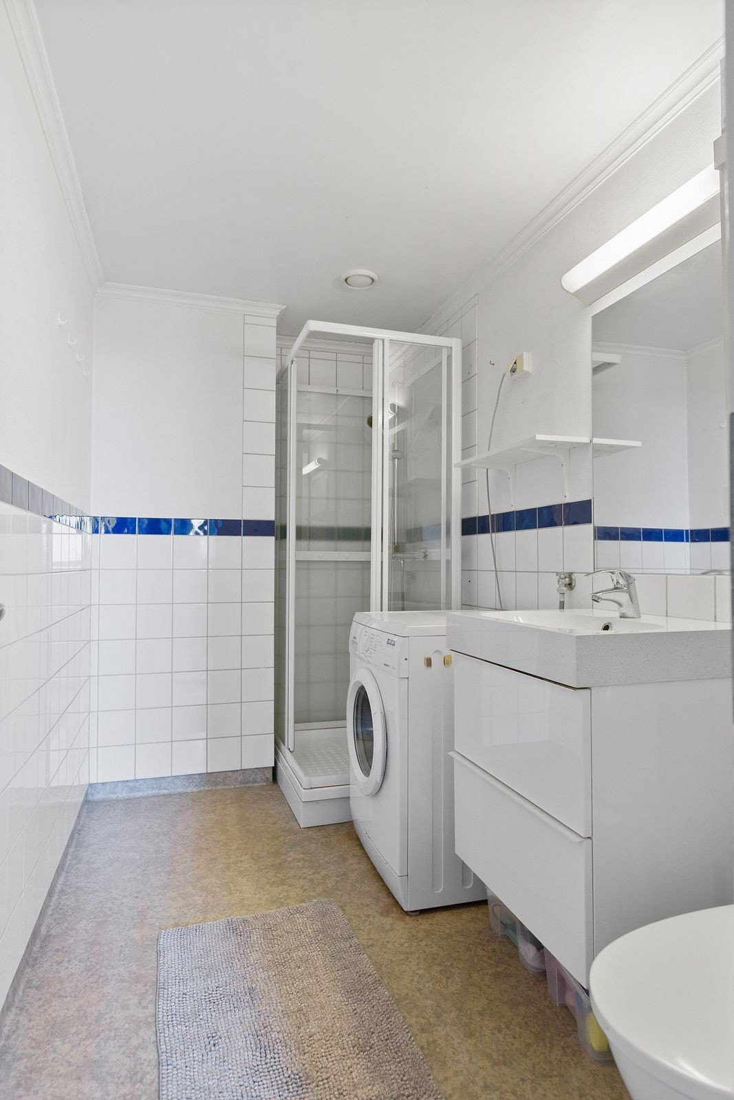 Bad med dusjkabinett, toalett, servant og vaskemaskin Galleribilde