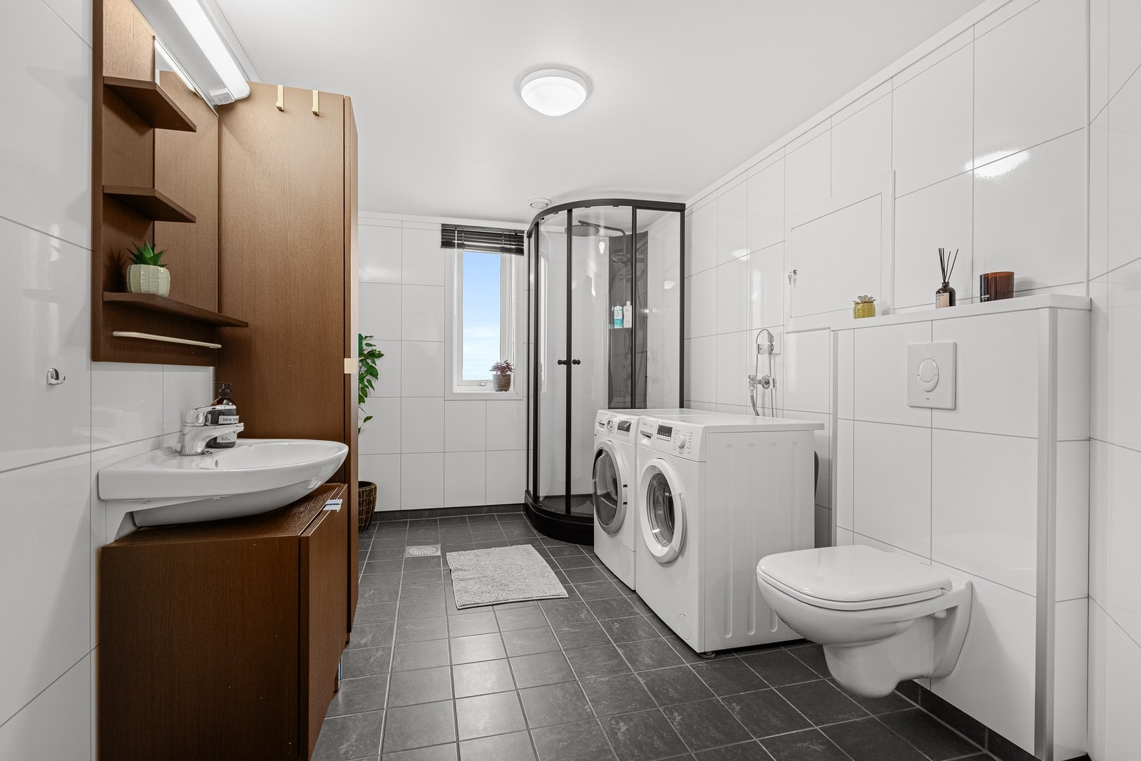 Bad med nyere dusjkabinett og opplegg til vaskemaskin og tørketrommel Galleribilde