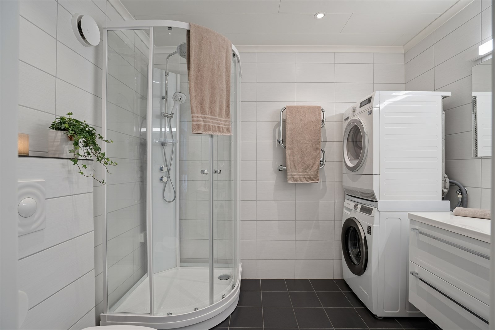 Badet er pent flislagt og er innredet med moderne servantskap, dusjkabinett, vegghengt toalett og opplegg for vaskemaskin/tørketrommel. Galleribilde