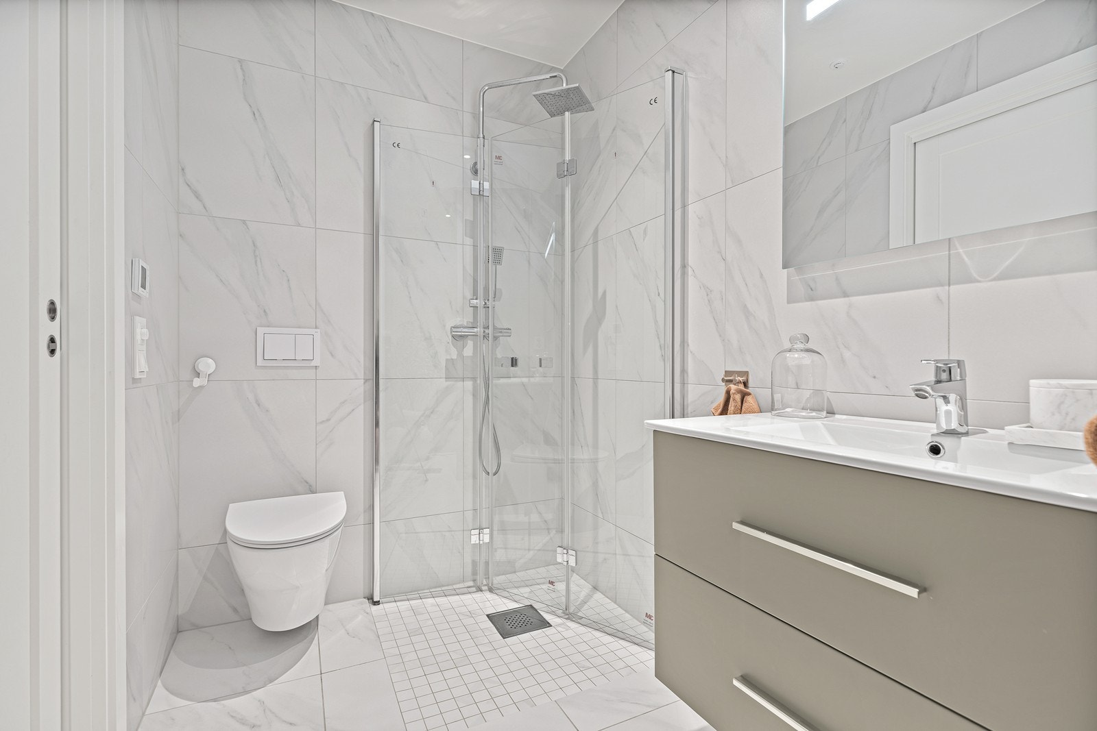 Badet er innredet med nedfelt servant, vegghengt toalett og dusjhjørne med innfellbare dører Galleribilde