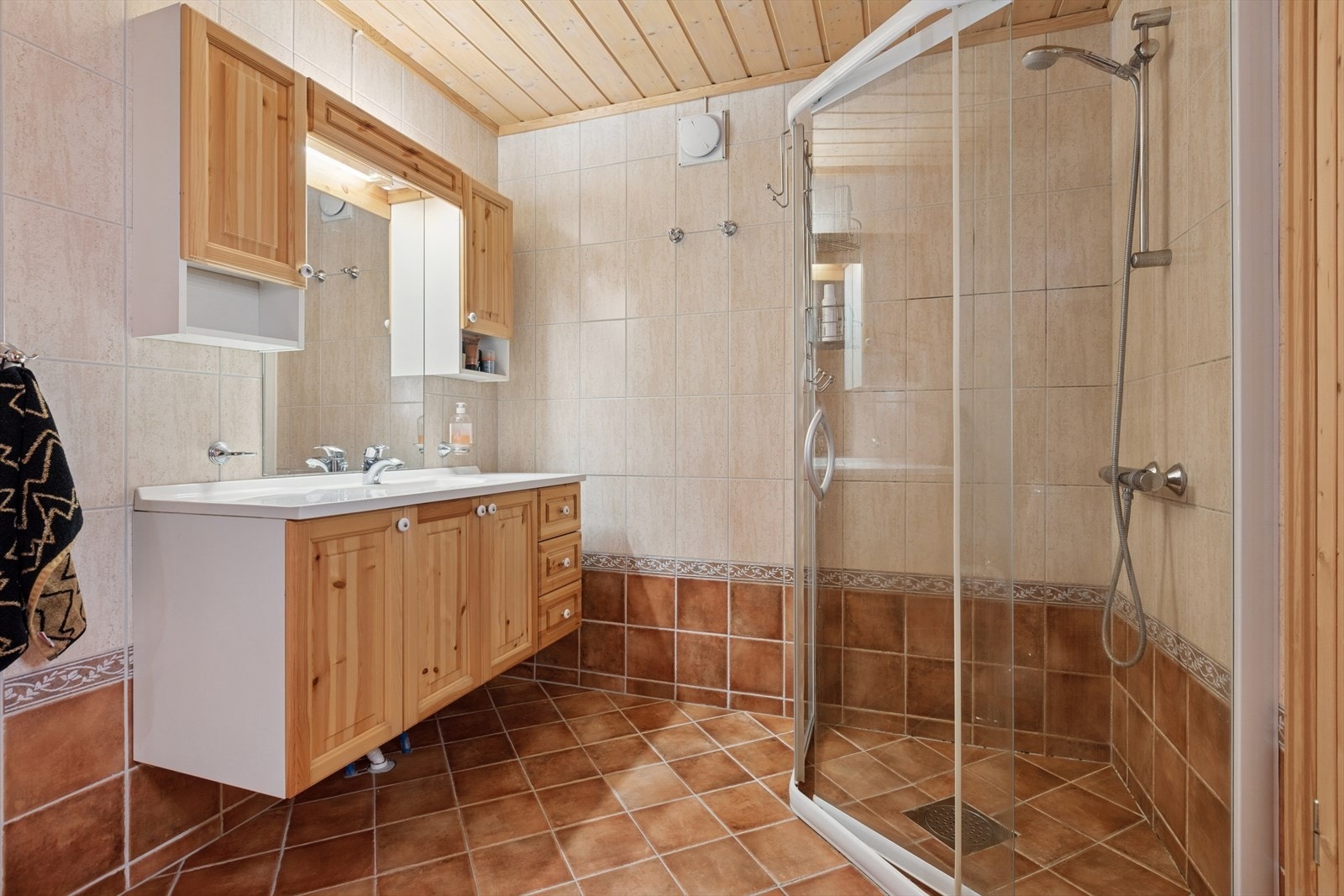 Bad i underetasjen med flislagt gulv, dusjhjørne og profilert innredning. Galleribilde